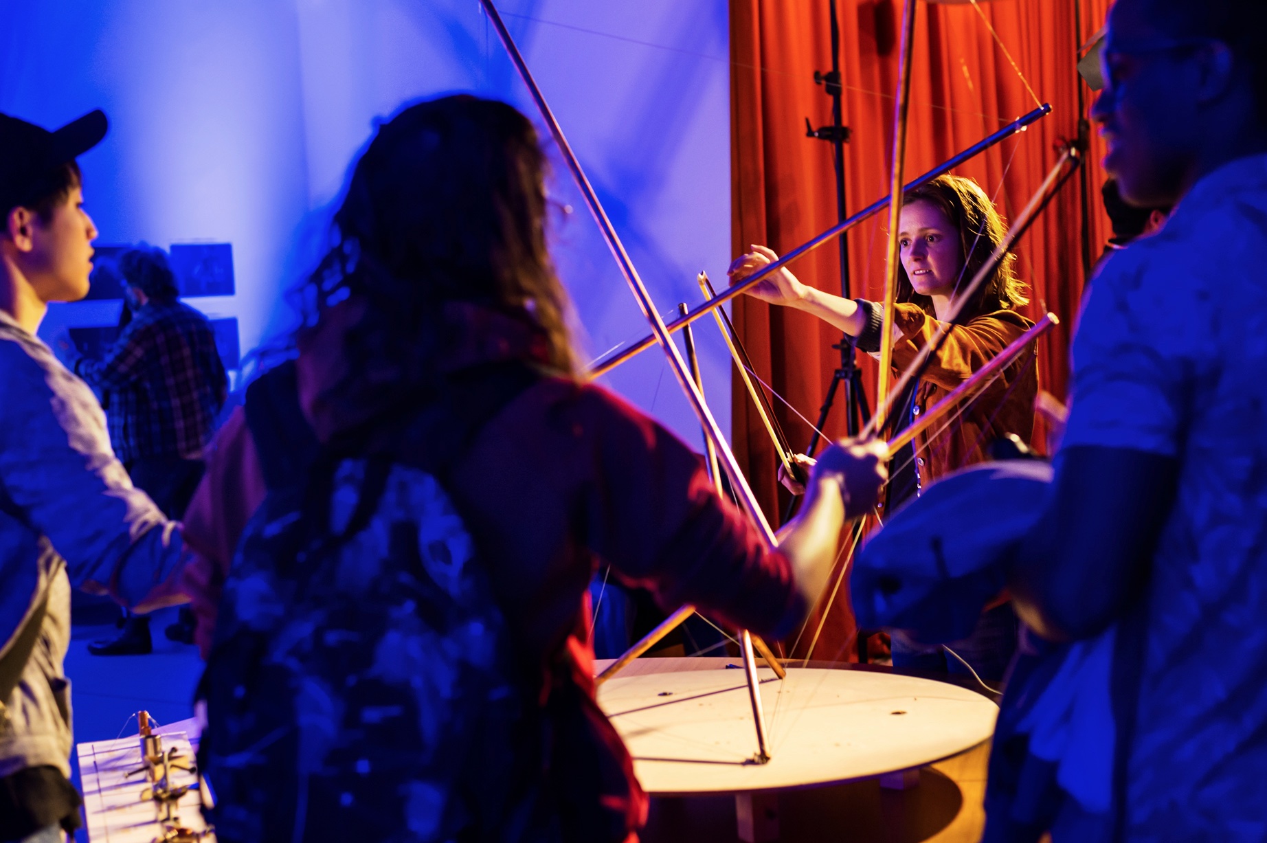 A photo of Tabita with her Tensegrity instrument. The picture is of the instrument with her in the centre performing on it.