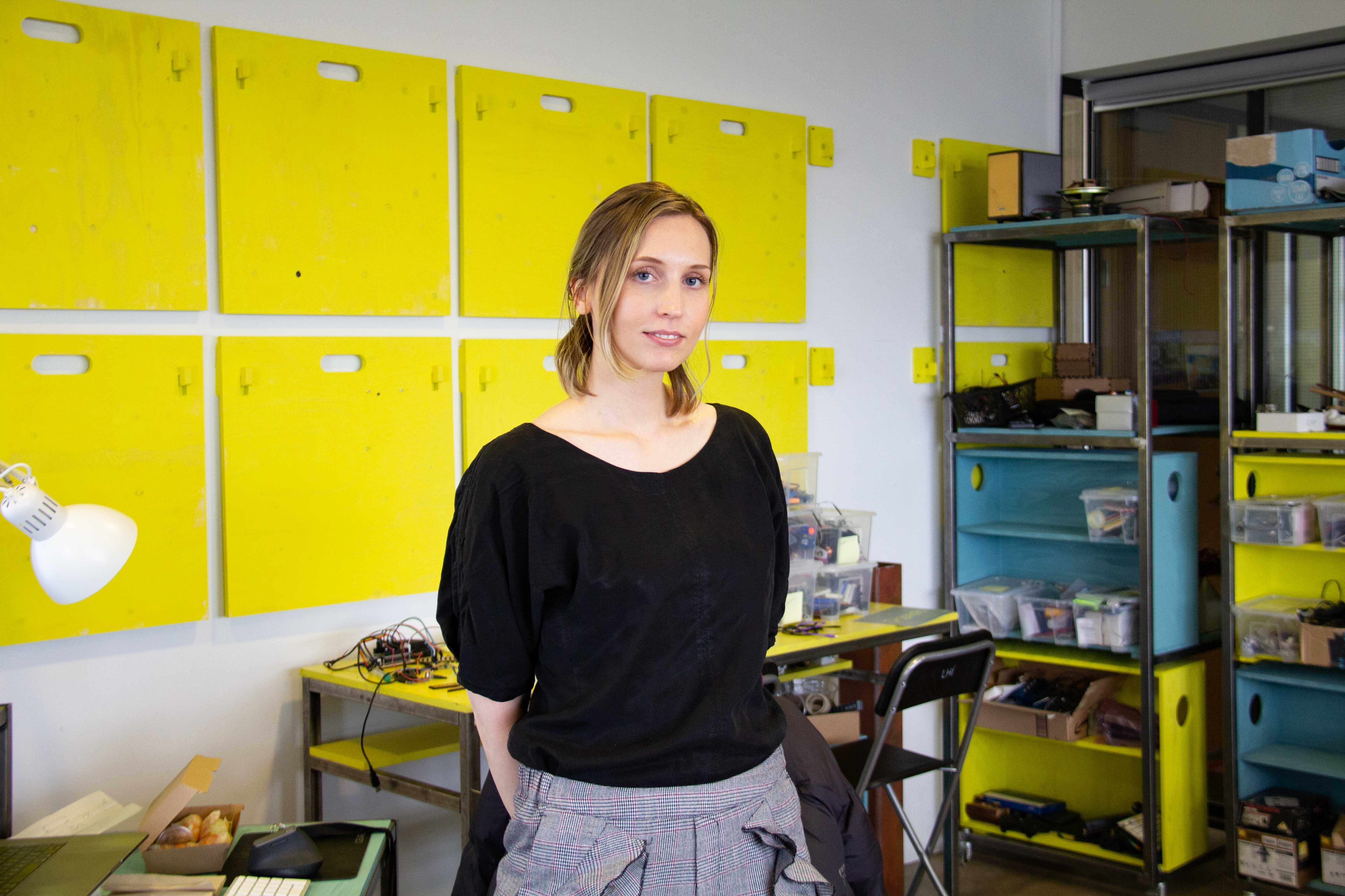 A young woman standing in front of a yellow and blue shelving system