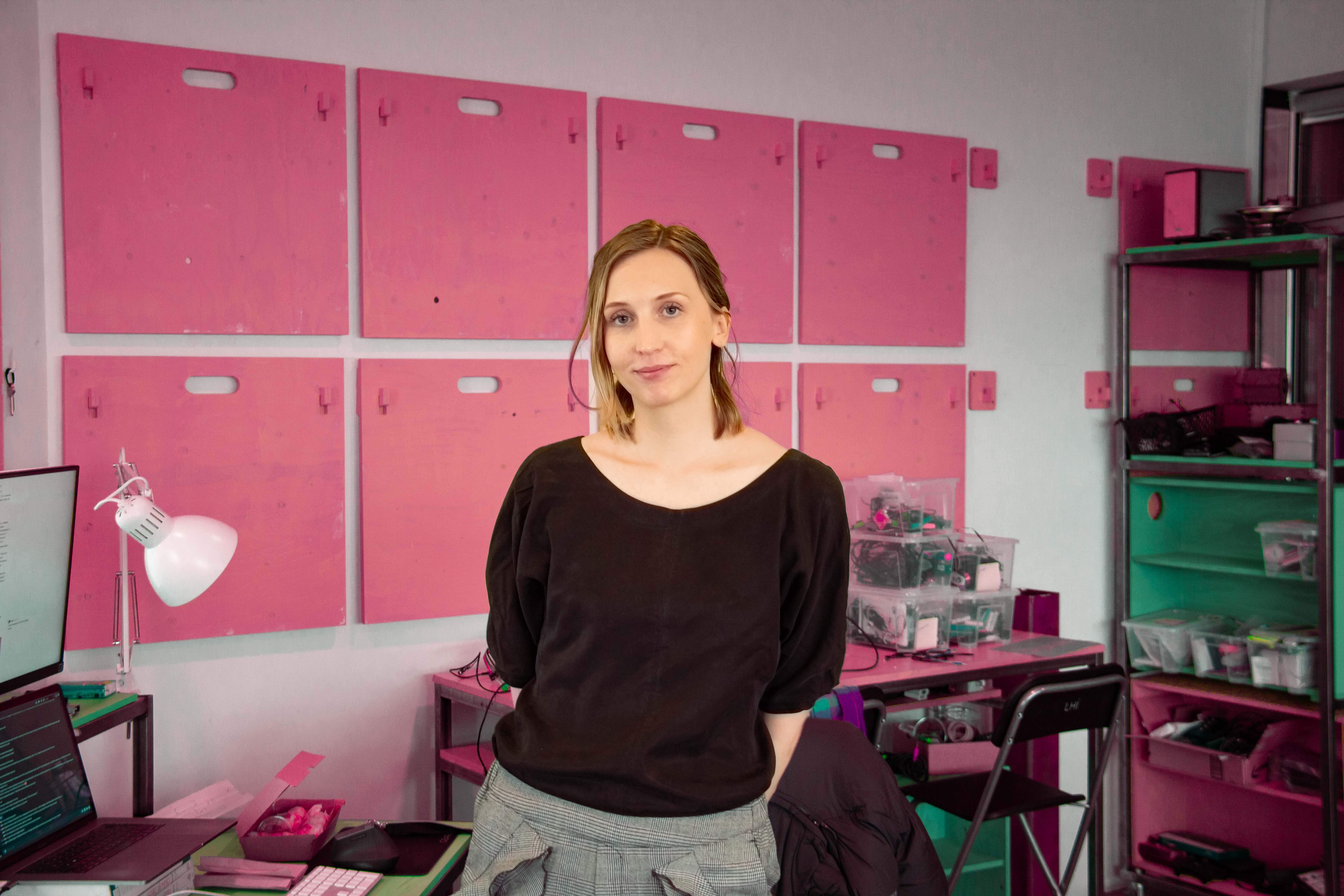 A young woman standing in front of a pink shelving system in the laboratory