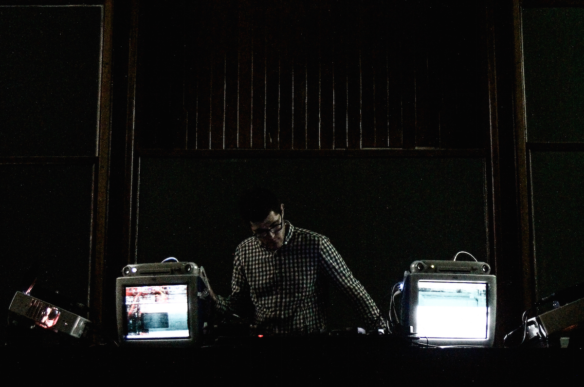 Jonathan performing in a dark location with two bright tube screens on either side.