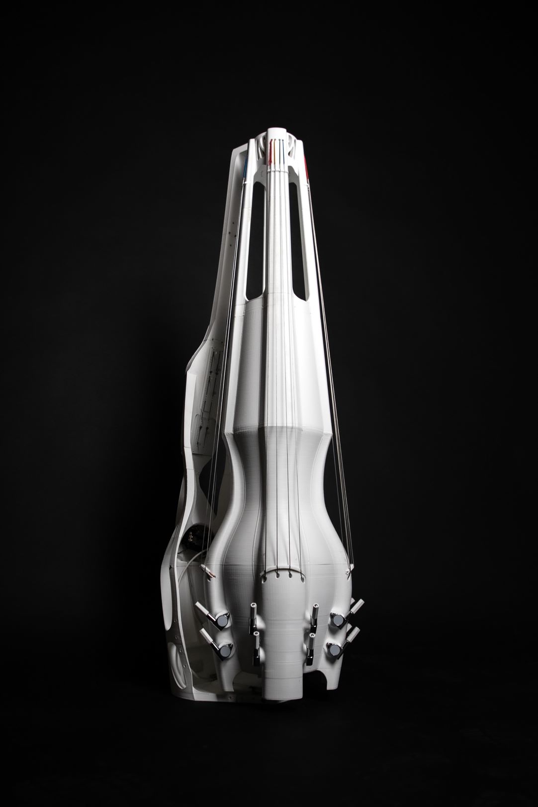 White 3D-printed upright instrument with 4 sets of strings. Black background.
