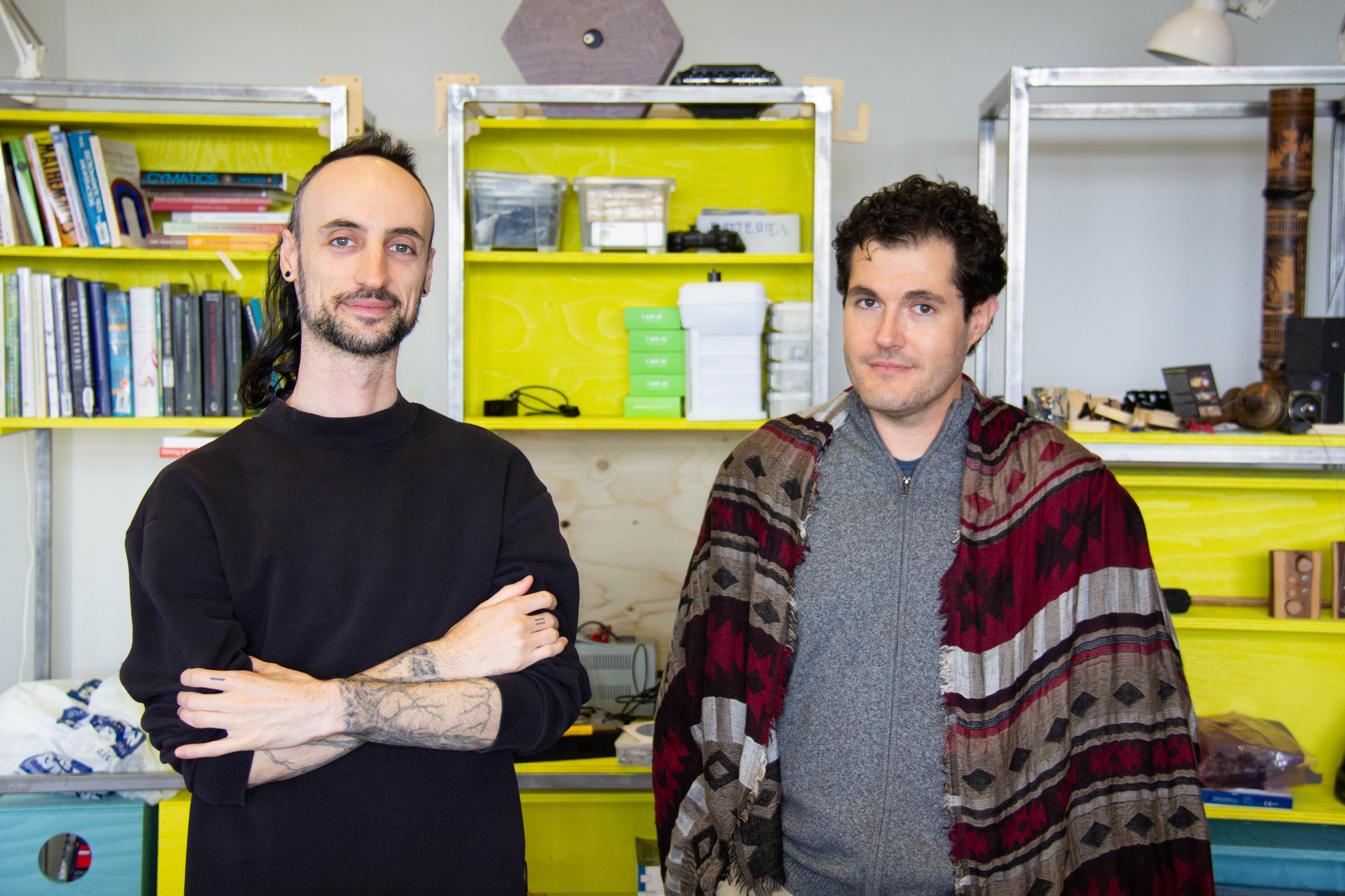 Two people standing in front of a yellow shelving system.