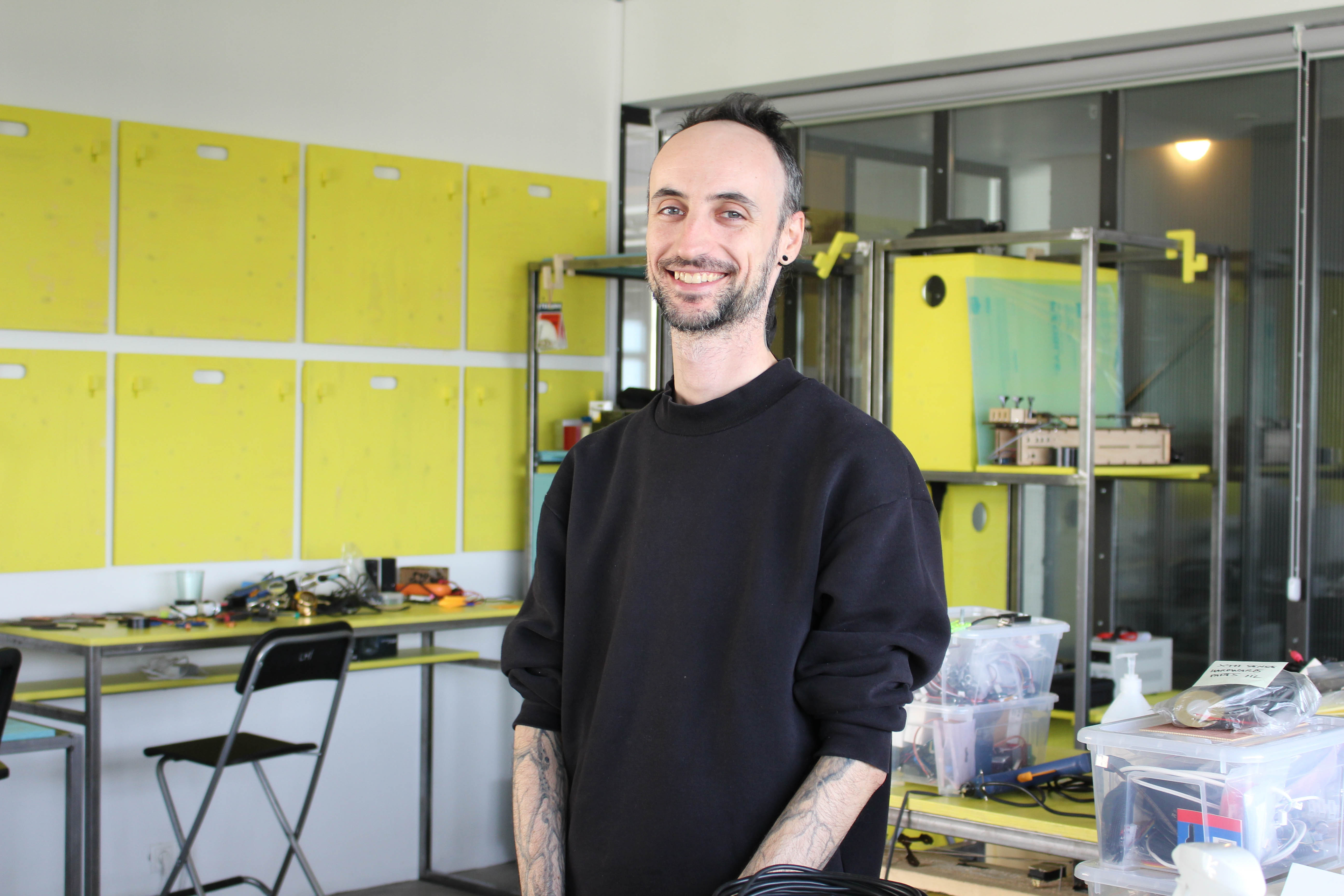 A person smiling in the lab, yellow shelving system in background