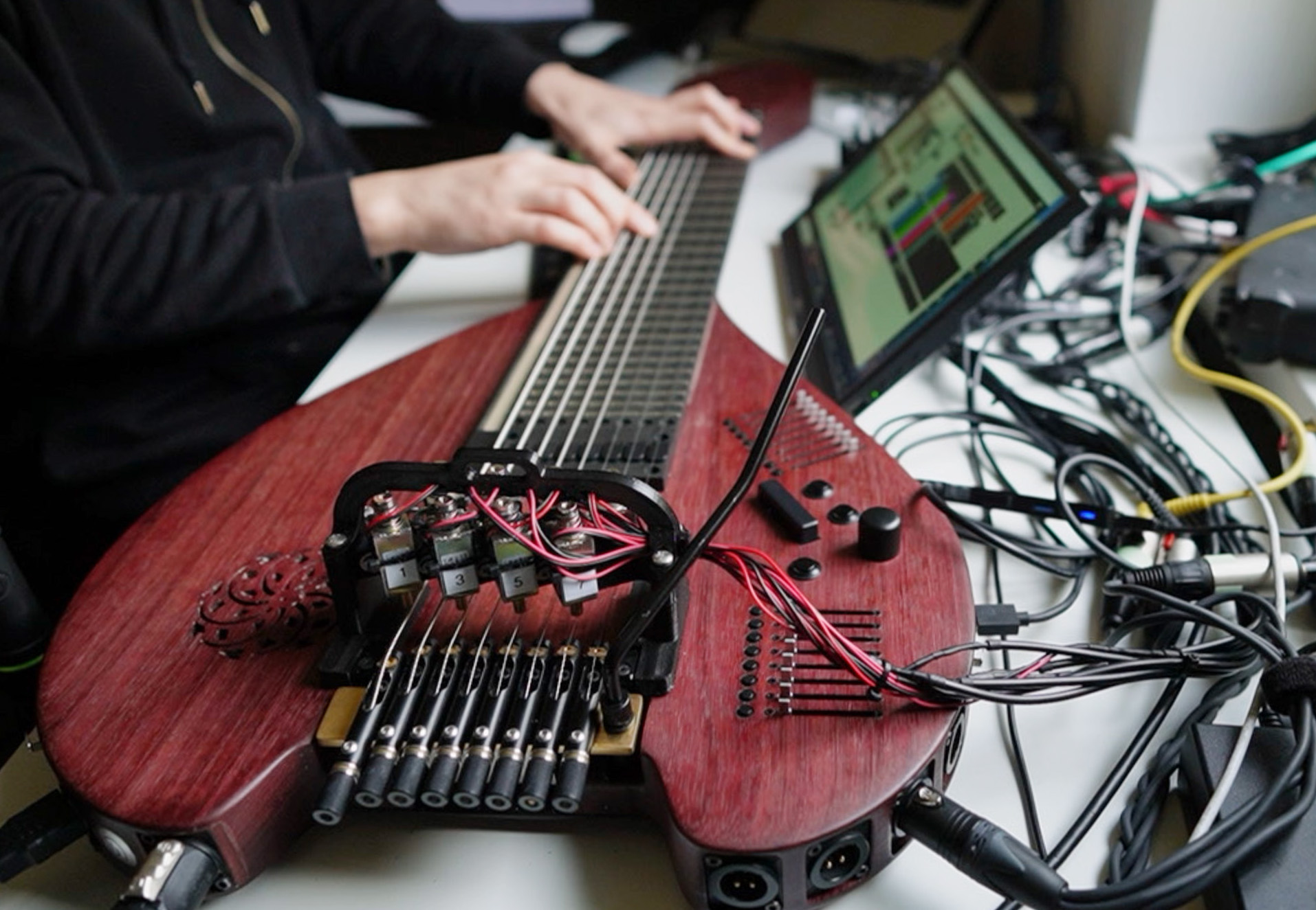 The Sophtar being played on a white table by a window. There are many cables connecting the instrument to other devices.