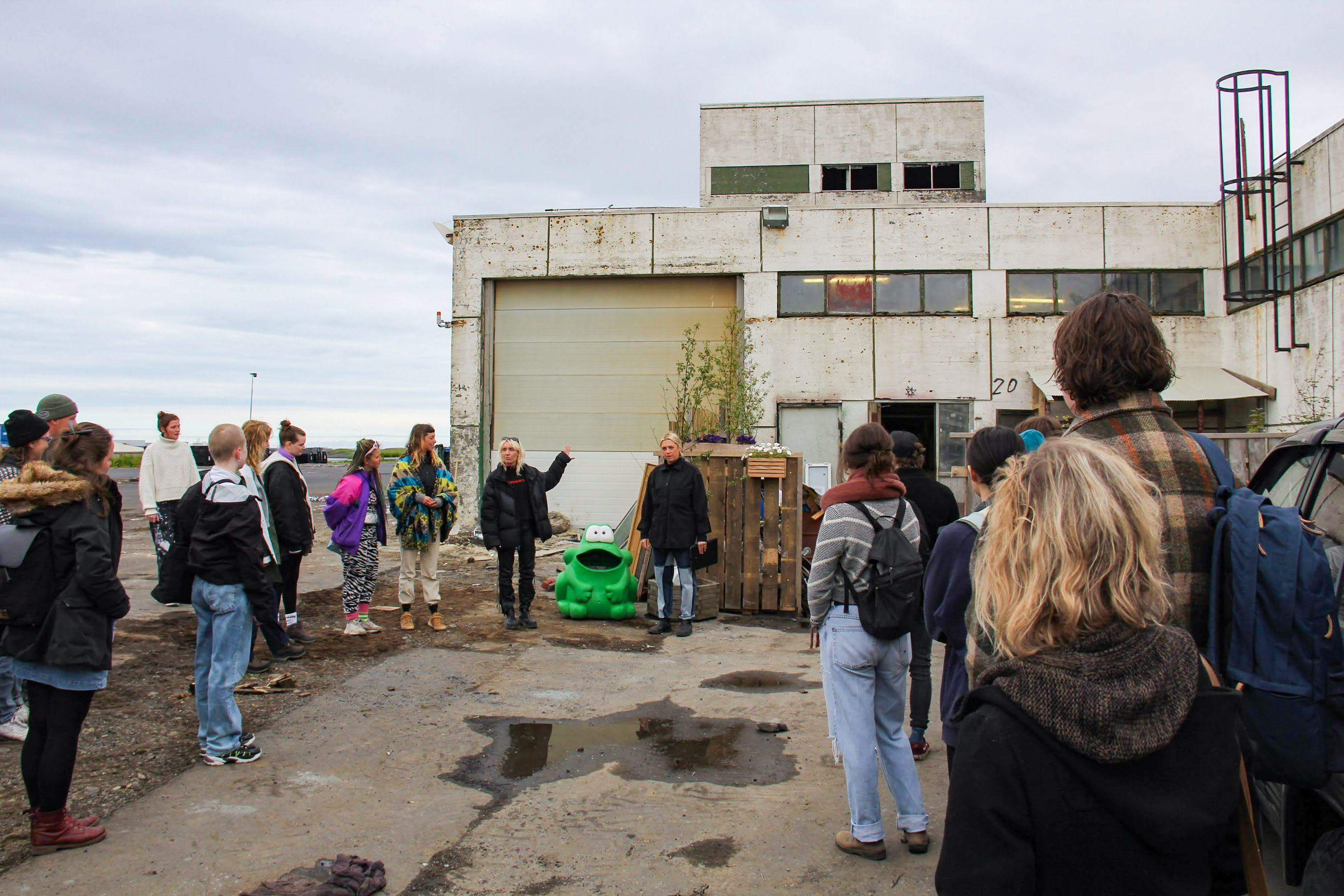 A group of people standing outside an industrial looking building.