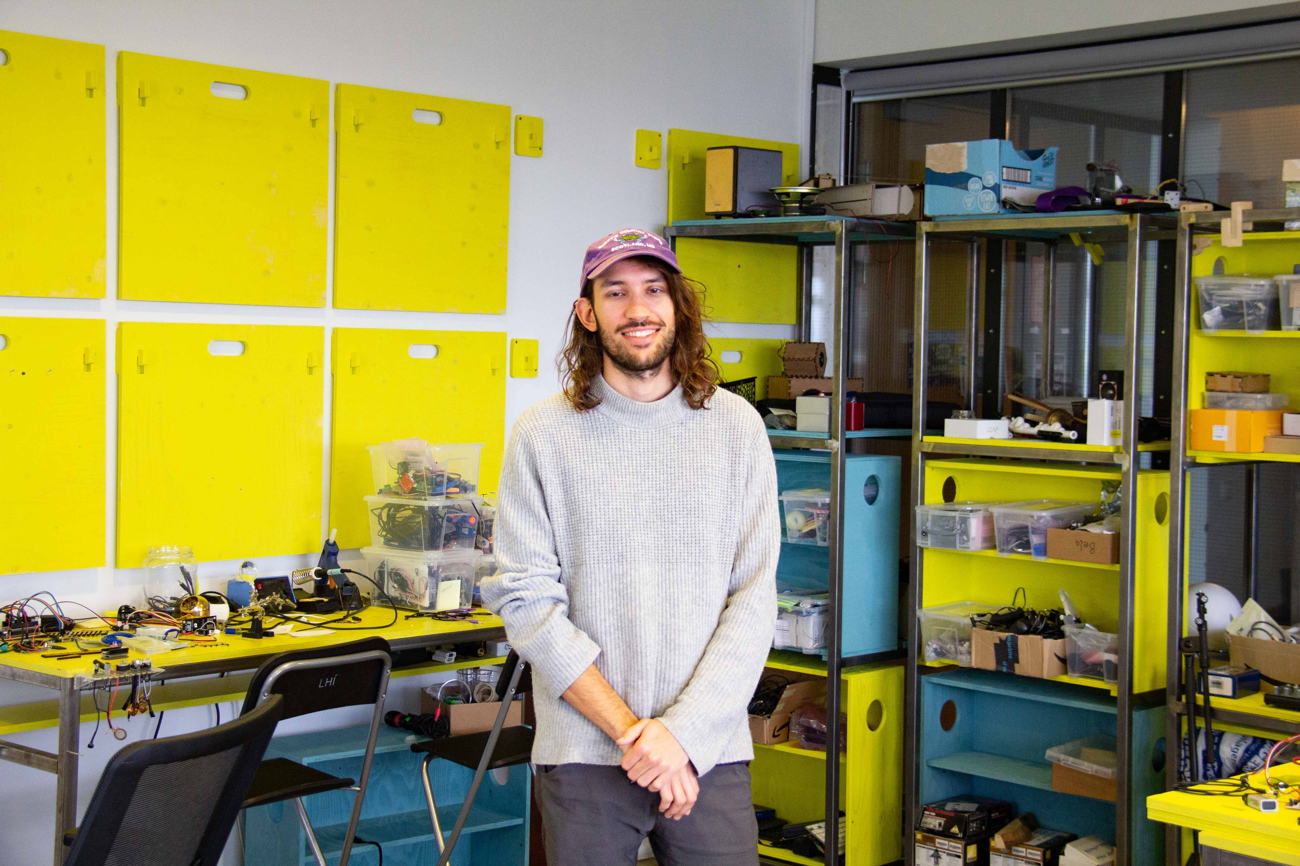 A young man standing in front of a yellow and blue shelving system