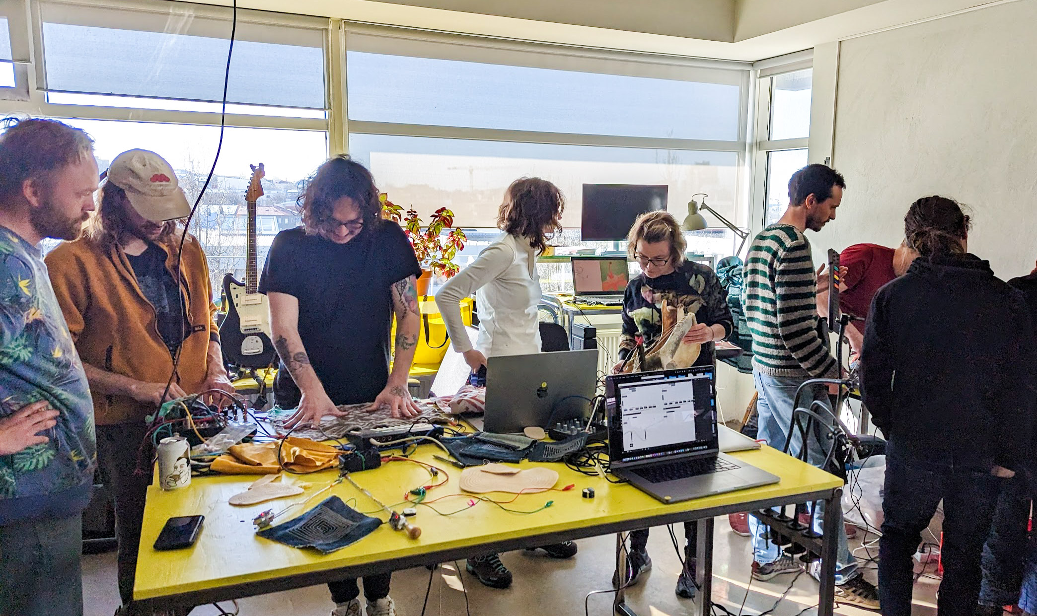 People surrounding a yellow table with loads of odd instruments