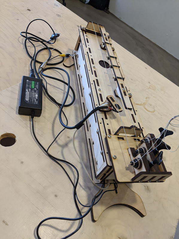 A complex prototype of a long box-shaped instrument with audio and electric cables connected.